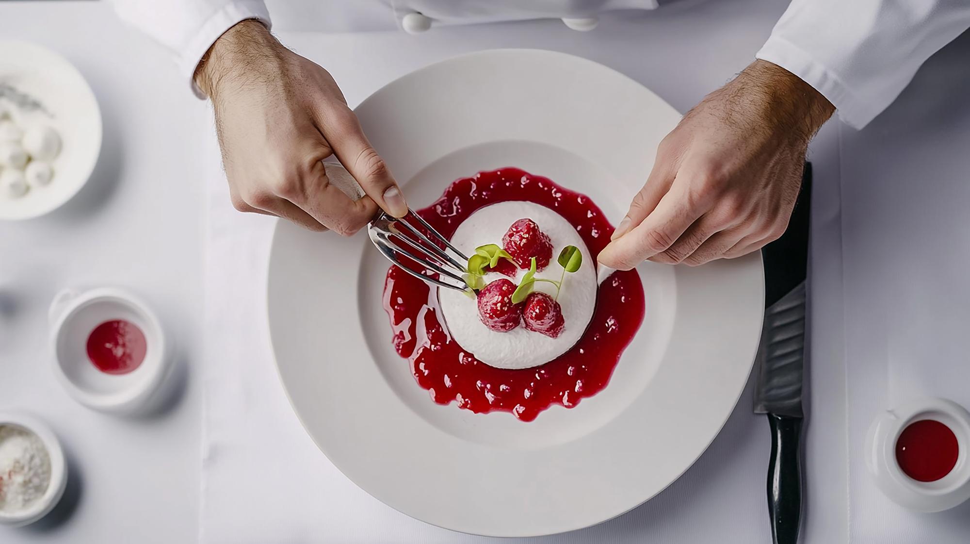 Chef demonstrating plated dessert on marble table